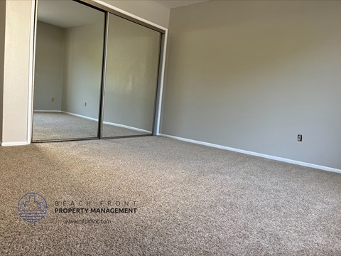 A carpeted room with a sliding glass door and a logo for Beach Front Property Management.